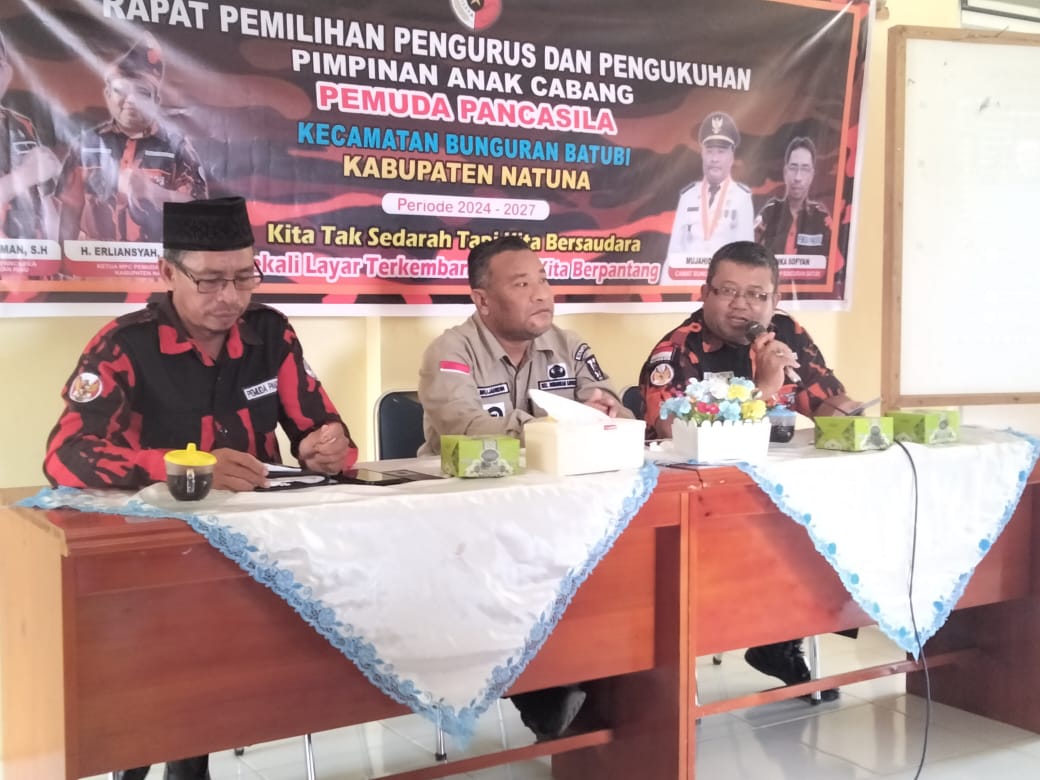 Pada tanggal 1 November 2024, suasana di Kecamatan Bunguran Batubi, Kabupaten Natuna, tampak lebih hidup dari biasanya. Aula yang telah dipersiapkan untuk rapat pemilihan pengurus dan pengukuhan Pimpinan Anak Cabang (PAC) Pemuda Pancasila mulai dipenuhi oleh berbagai tokoh masyarakat, anggota organisasi, dan tamu undangan. Mereka datang untuk menghadiri acara penting ini, yang bertujuan memperkuat struktur organisasi Pemuda Pancasila di tingkat kecamatan. Kehadiran Ketua Alpena, Ibu Rahayu Christinawati, menarik perhatian para peserta. Dengan penuh semangat, beliau menyampaikan pesan motivasi bagi anggota Pemuda Pancasila untuk terus berperan aktif dan solid dalam menjalankan program-program yang bermanfaat bagi masyarakat. Di sampingnya, tampak Ketua Pemuda Pancasila Bunguran Timur, Bapak Erliasyah, yang datang untuk memberikan dukungan moral kepada rekan-rekan di Bunguran Batubi. Kehadiran beliau seolah menjadi simbol kebersamaan dan persaudaraan lintas cabang. Selama acara berlangsung, beberapa aliansi dan organisasi turut memberikan sambutan. Masing-masing berbagi harapan agar PAC Pemuda Pancasila Bunguran Batubi mampu menjadi mitra aktif dalam pembangunan daerah. Pesan-pesan yang disampaikan menggambarkan antusiasme dan optimisme terhadap peran Pemuda Pancasila sebagai wadah kepemudaan yang dapat menjadi penggerak positif di tengah masyarakat. Ketika tiba saatnya pengukuhan, suasana berubah menjadi lebih khidmat. Para pengurus baru yang terpilih satu per satu dipanggil ke depan untuk menerima pengukuhan resmi. Sorak sorai dan tepuk tangan dari peserta mengiringi setiap pengurus yang dipanggil, menambah semangat mereka yang akan memimpin PAC Pemuda Pancasila Bunguran Batubi dalam periode mendatang. Acara ditutup dengan sesi foto bersama dan ramah-tamah. Para peserta saling berbagi cerita, bertukar pengalaman, dan mempererat tali persaudaraan. Tak hanya sebagai momen pemilihan dan pengukuhan, acara ini menjadi sarana penting untuk menjalin sinergi di antara berbagai organisasi dan aliansi yang hadir, dengan harapan besar bahwa Pemuda Pancasila di Natuna dapat terus berkiprah dalam menjaga nilai-nilai Pancasila dan membangun masyarakat yang lebih baik. Dengan pengurus yang baru dikukuhkan, PAC Pemuda Pancasila Bunguran Batubi kini memiliki energi dan tekad yang baru untuk melangkah maju, membawa semangat perubahan positif di kecamatan mereka.